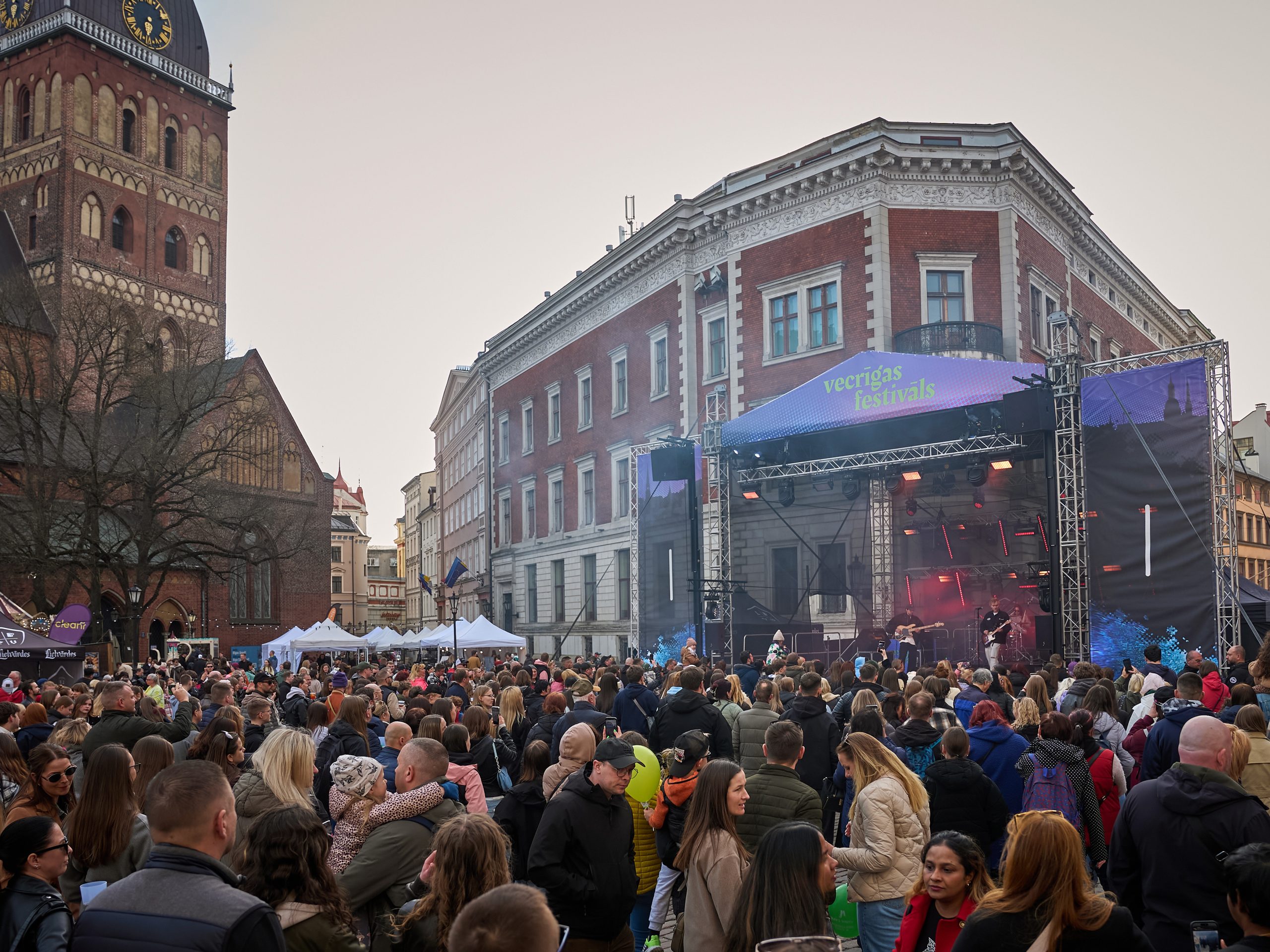 Doma laukumā, muzikantu grupa uzstājās uz lielas skatuves. Laukumā ir daudz cilvēku-skatītāju
